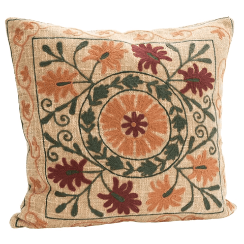 A square decorative throw pillow with a vintage-style embroidered or printed floral medallion pattern in orange, burgundy, and green on a beige background.