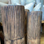 Two rustic dark brown wooden vases with a vertically grooved, textured finish, shown in a home decor setting with neutral-toned pillows in the background.
