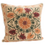 A square decorative throw pillow with a vintage-style embroidered or printed floral medallion pattern in orange, burgundy, and green on a beige background.